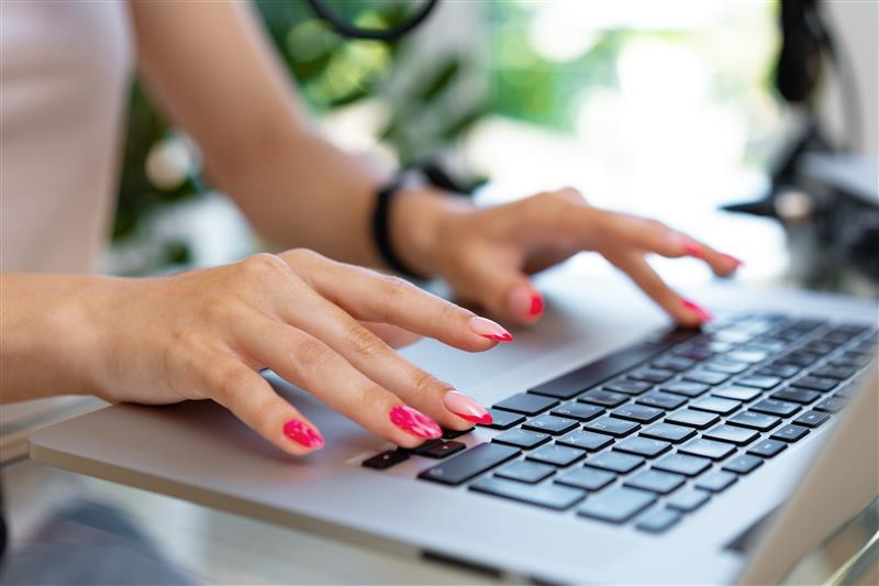 Close up of woman's hands typing on a laptop keyboard